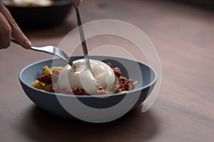 Closeup of pesto conchiglie with sundried tomatoes and cutting burrata cheese served in blue bowl photo