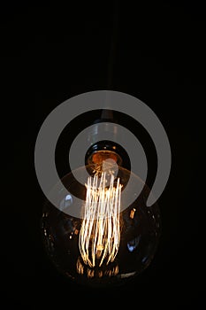 Closeup pf an antique vintage edison style light bulb against dark