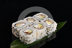 Closeup philadelphia roll sushi with eel cucumber, cream cheese and sesame seeds served on black background