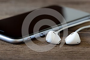 Closeup phone and earbud on wood