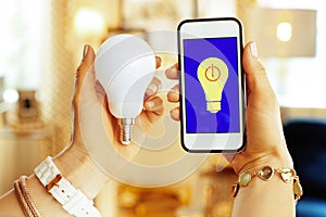 Closeup on phone with smart home app and smart lamp in hands