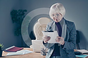 Closeup photo of aged business lady arms e-reader browsing reader information lean table office wear specs costume suit