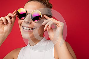 Closeup photo of attractive smiling happy young blonde woman wearing everyday stylish clothes and modern sunglasses