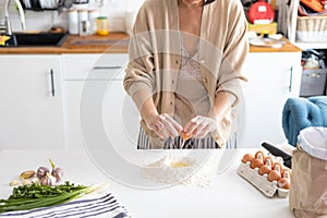 Closeup photo of baker cracking egg for dough. Woman preparing dumplings in kitchen at home