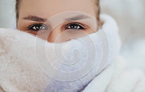 Beautiful brunette female face half covered with winter knitted scarf