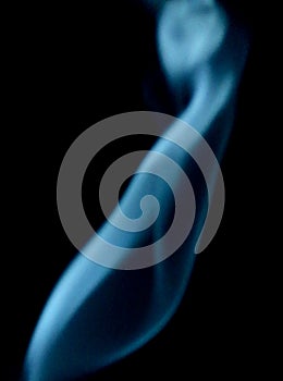 Closeup photo of blue smoke on a black background.