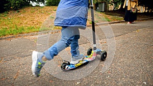 Closeup photo of boy`s feet riding on children kick scooter at park