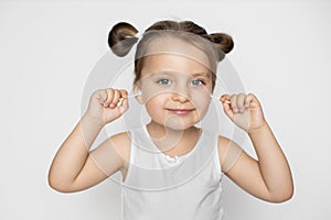 Closeup photo of charming little baby girl, wearing white tank top, cleaning her ears with cotton swabs, posing over the