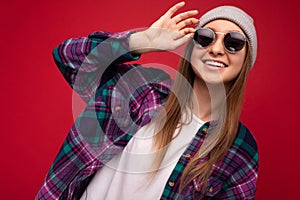 Closeup photo of charming smiling young blonde woman isolated over red background wearing colourful stylish shirt grey