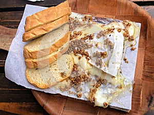 A closeup photo of a delicious meal of Warm Brie, candied pecans, honey, and a baguette