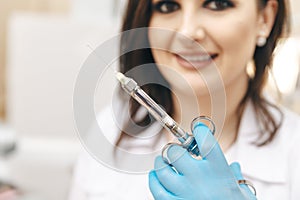 Closeup photo of female dentist in the dental room holding oral syringe.
