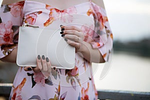 Closeup photo of female hand holding white leather purse. Empty