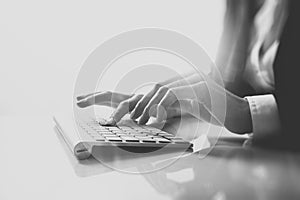 Closeup photo of female hands typing text on a wireless keyboard. Business woman working at the office. Visual effects