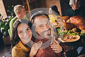 Closeup photo of full family gathering bearded husband wife cuddle beaming smiling hold hands finish eat meal sit served