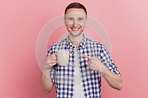 Closeup photo of handsome young man happy positive smile point finge mug coffee promo advice isolated pastel background