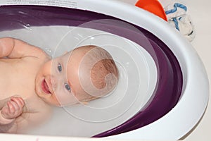 A closeup photo of happy baby enjoying bath time in her baby bath tub