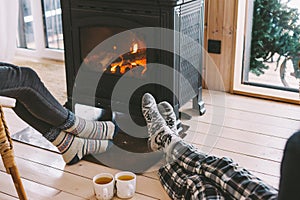 Closeup photo of human feet in warm woolen socks over fire place