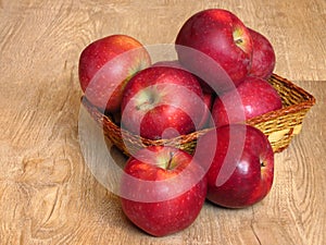 Juicy red organic apples in a basket on oak tree wood background. Autumn Fall season orchard harvest production.