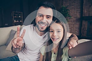 Closeup photo of little adorable lady her handsome daddy sit comfy sofa making selfies showing v-sign symbol spend