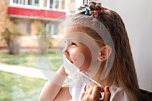 Closeup photo of little cute girl keep self-isolation wear protective mask at home