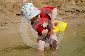 Closeup photo of a little girl. A child plays with the sand on the beach.