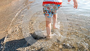 CLoseup photo of little toddler boy stepping in sea water at beach