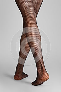 Closeup photo of long slim female legs in black fishnet tights