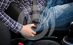 Closeup photo of man seating on drivers seat and fastening belt
