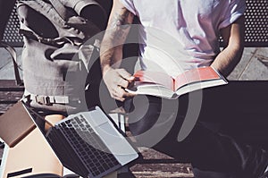 Closeup photo man wearing white tshirt sitting city park and reading book. Studying at the University, preparation for photo