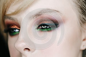 Closeup photo of opened woman eye with beautiful bright makeup, brown and green smoky eyes looking right side
