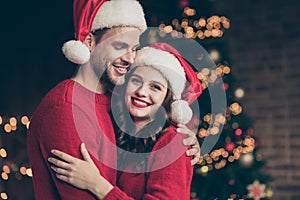 Closeup photo of overjoyed couple spending christmas time eve in decorated garland lights room near x-mas tree indoors