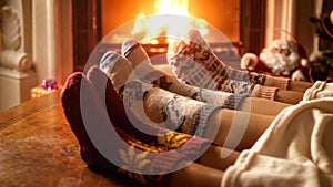 Closeup photo of parents with child in woolen socks warming at night by the fireplace