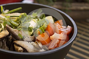 A closeup photo of poke with tomato, slices of shiitake and chives.