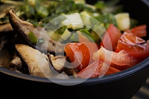 A closeup photo of poke with tomato, slices of shiitake and chives.