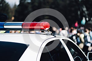 Closeup photo of police car with blue and red siren on the roof and defocused background.