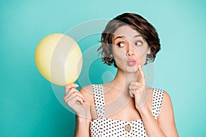 Closeup photo of pretty lady holding big yellow balloon bubble look side finger on chin tricky person wear casual white