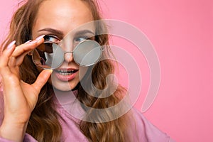 Closeup photo of pretty positive surprised young blonde curly woman isolated over pink background wall wearing casual