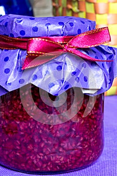 Closeup photo, raspberry jam-jar decorated with ribbon, craft paper