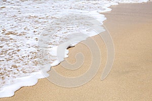 Closeup photo of sea white foam wave line and beach clean sand