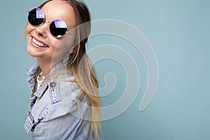 Closeup photo shot of attractive happy smiling young blonde woman wearing summer casual clothes and stylish sunglasses