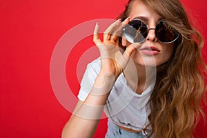 Closeup photo shot of beautiful asking thoughtful young dark blonde woman wearing casual clothes and stylish sunglasses