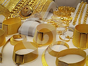 Closeup photo of a showcase with 24 carat golden bracelets, ring and necklace in a shop