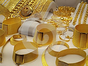 Closeup photo of a showcase with 24 carat golden bracelets, ring and necklace in a shop photo