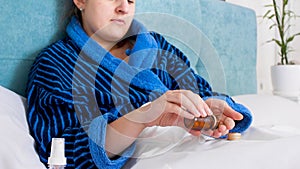 Closeup photo of sick woman pouring pills from glass botle in hand