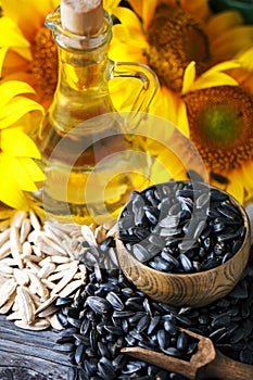 Closeup photo of sunflowers and sunflower oil with seeds on on a wooden table. Bio and organic concept of the product.