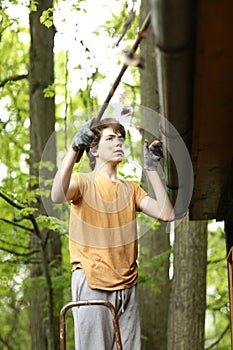 Closeup photo of teenager boy cleaning roof from old leafs
