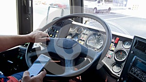 Closeup photo of truck driver typing on smartphone while driving. Danger in transport. Irresponsible driver