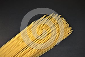 Closeup photo of uncooked spagetti pasta isolated on black background.