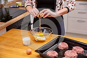 Closeup photo of woman breaking egg in glass bowl