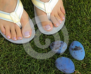 Closeup photo of woman feet in flip flop standing on green grass